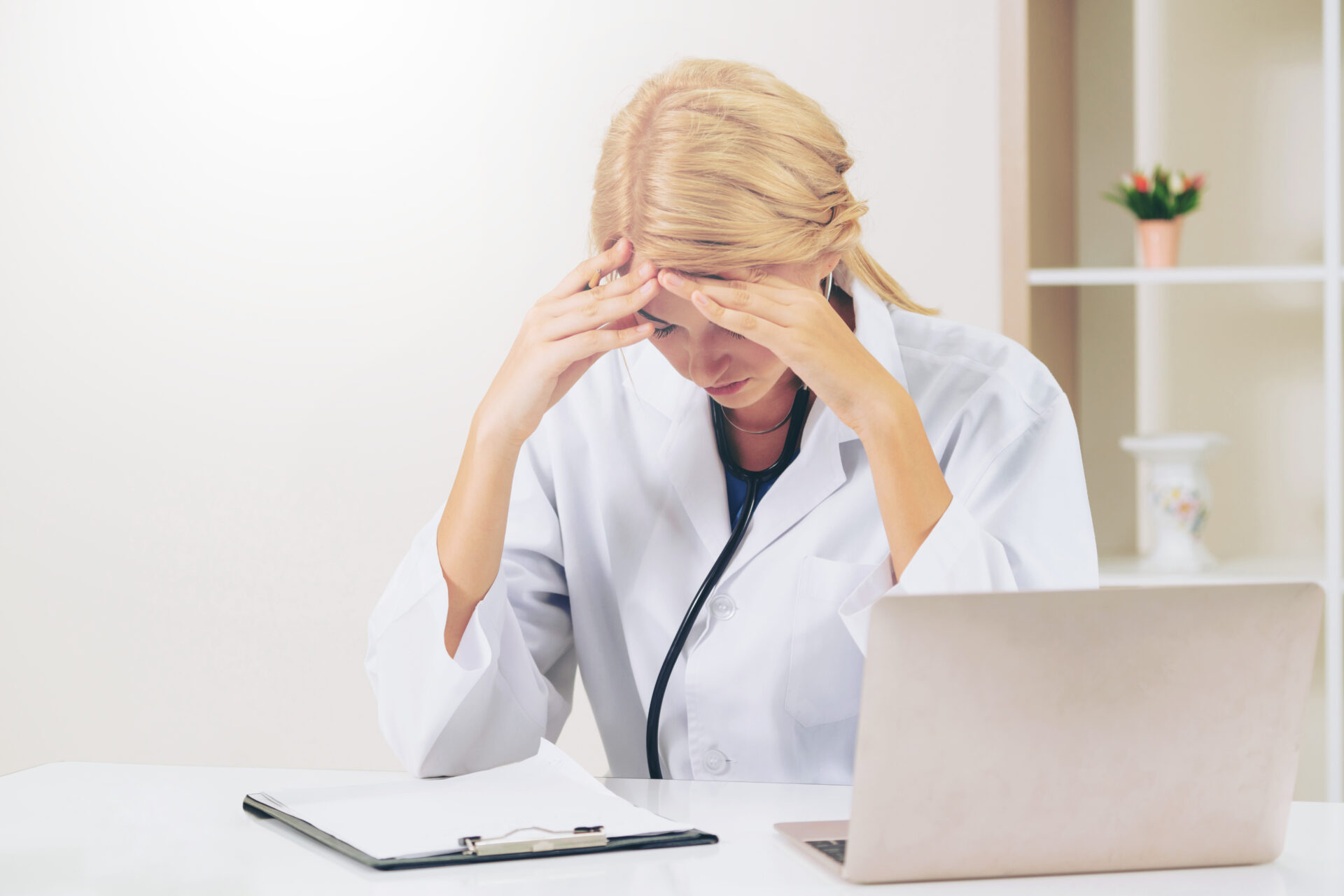 Serious doctor with her head down working in hospital office. Medical and healthcare concept.