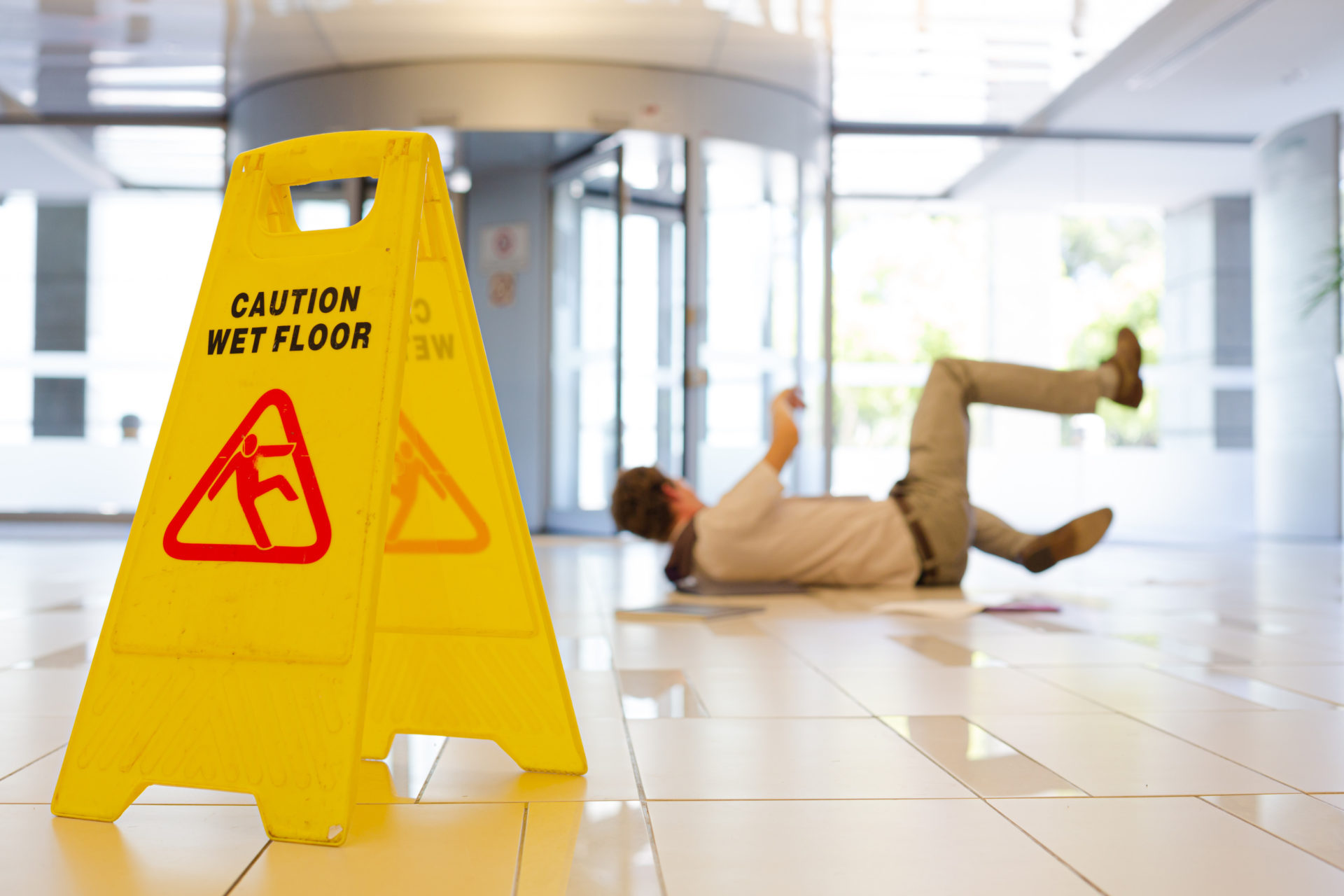 Caution Wet Floor sign on a wet floor - male falling on the floor