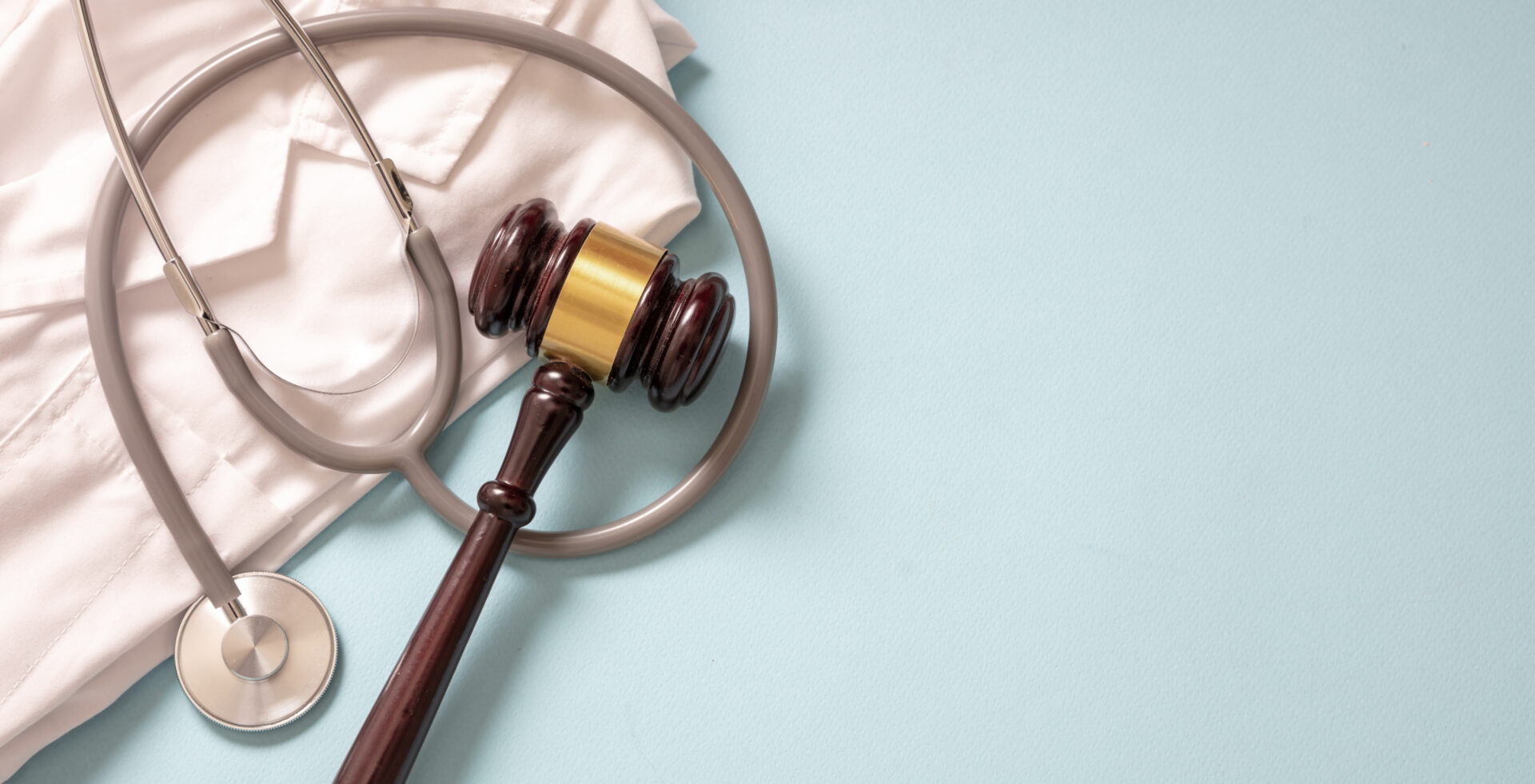 court gavel on top of a stethescope and doctor lab gown