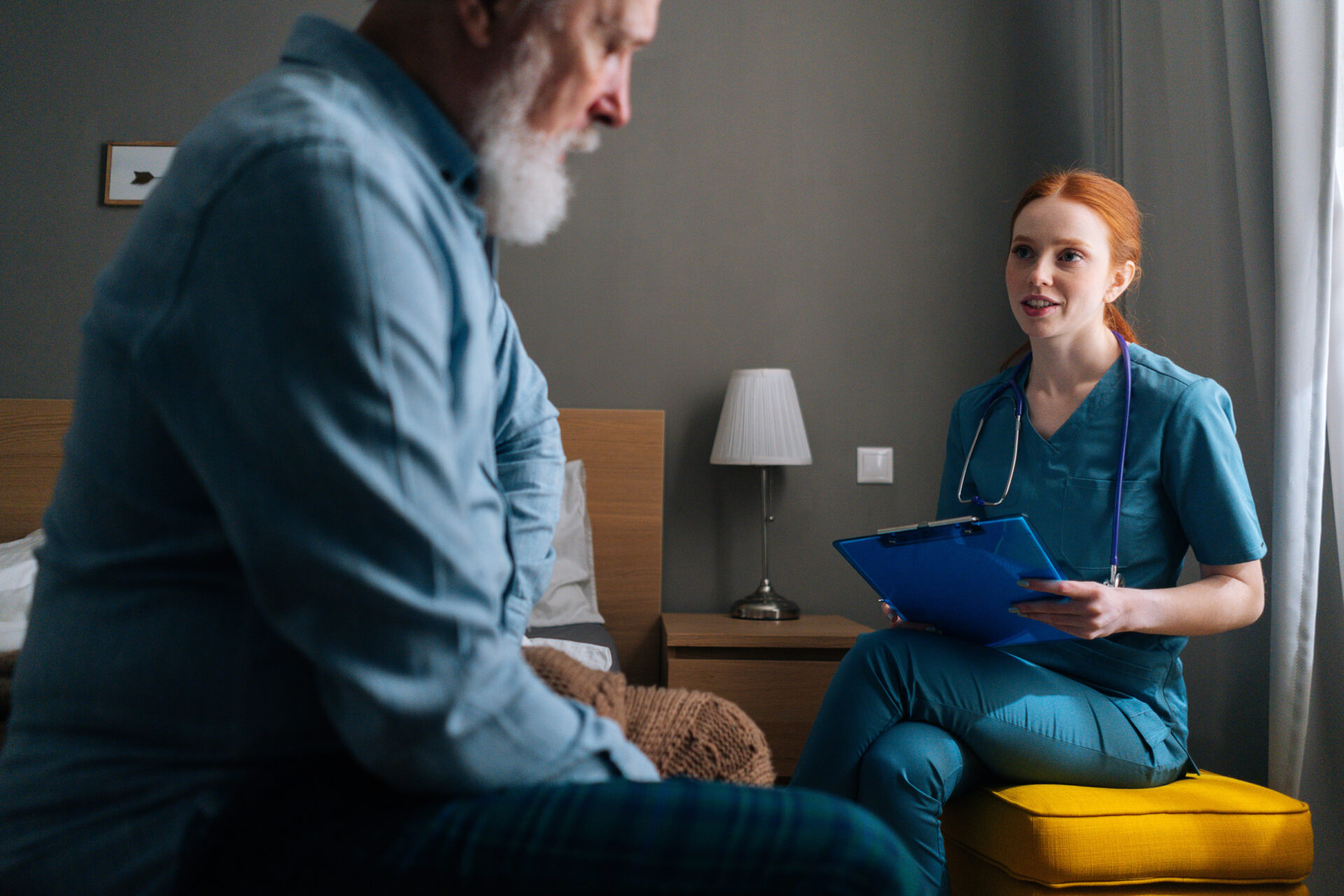 female nurse speaking with patient sitting in a bed at a hospital room