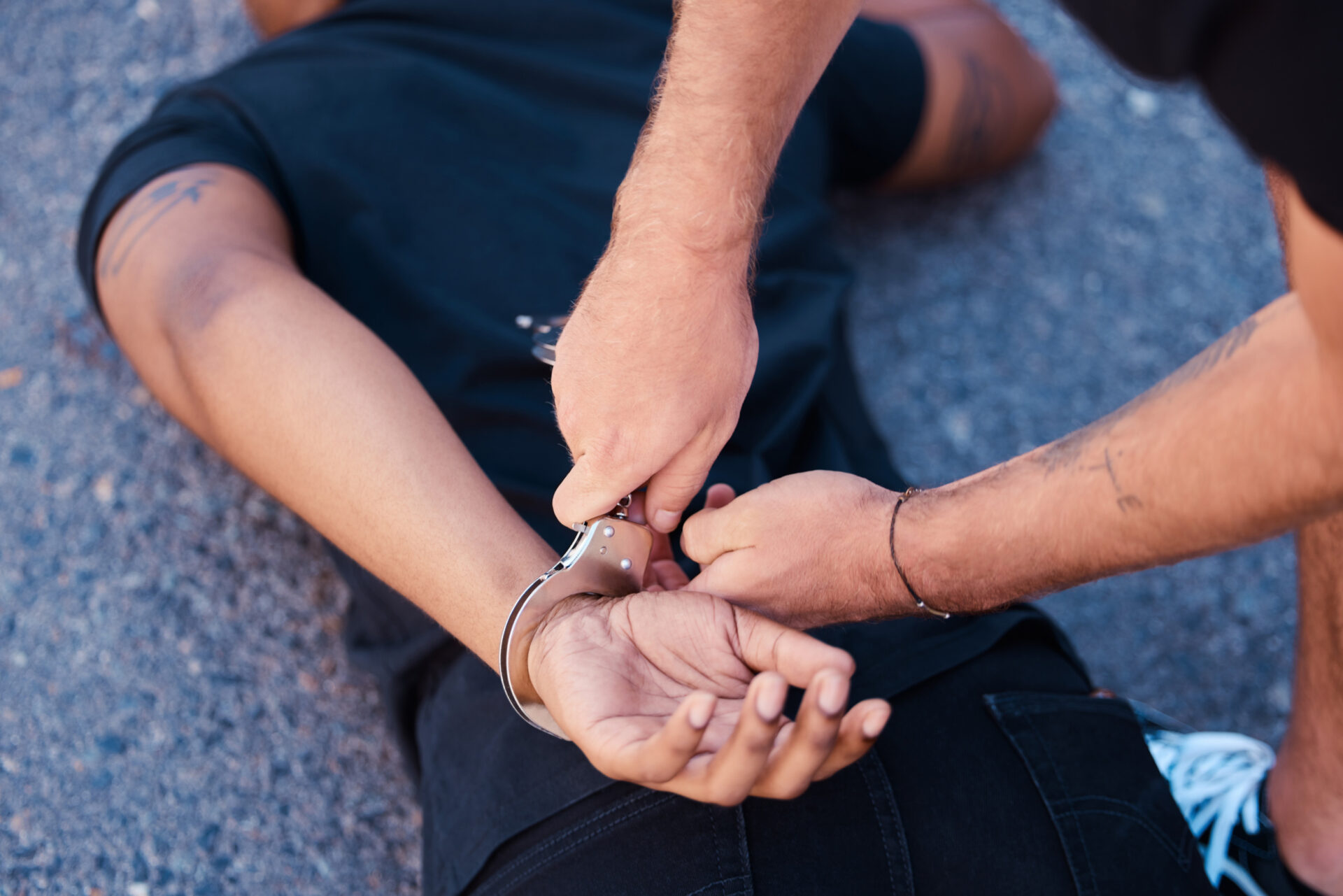 man getting arrested on the ground by a police officer.