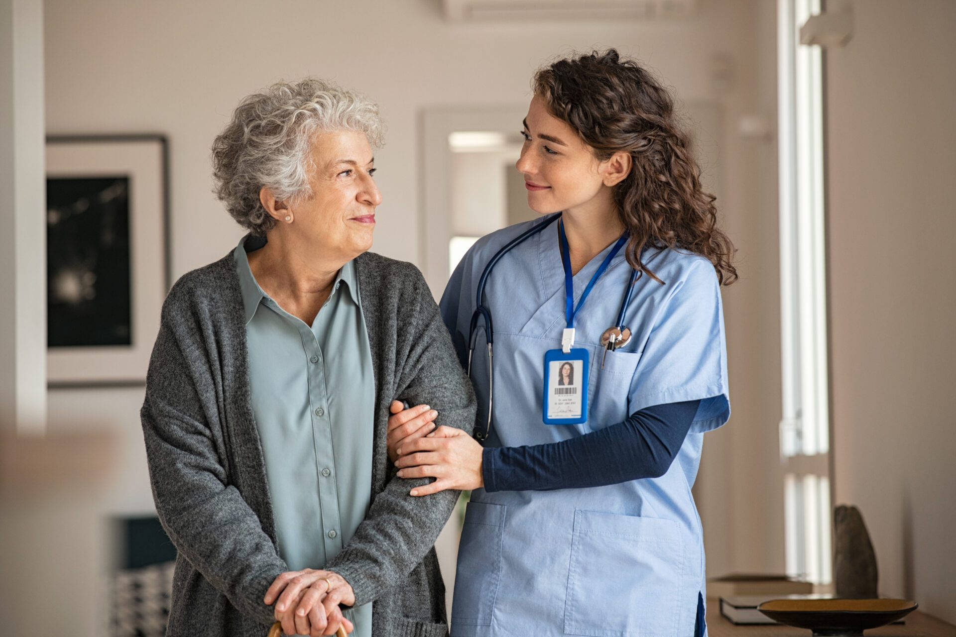 An elderly woman being compassionately escorted by a caring nurse, providing attentive support and guidance.