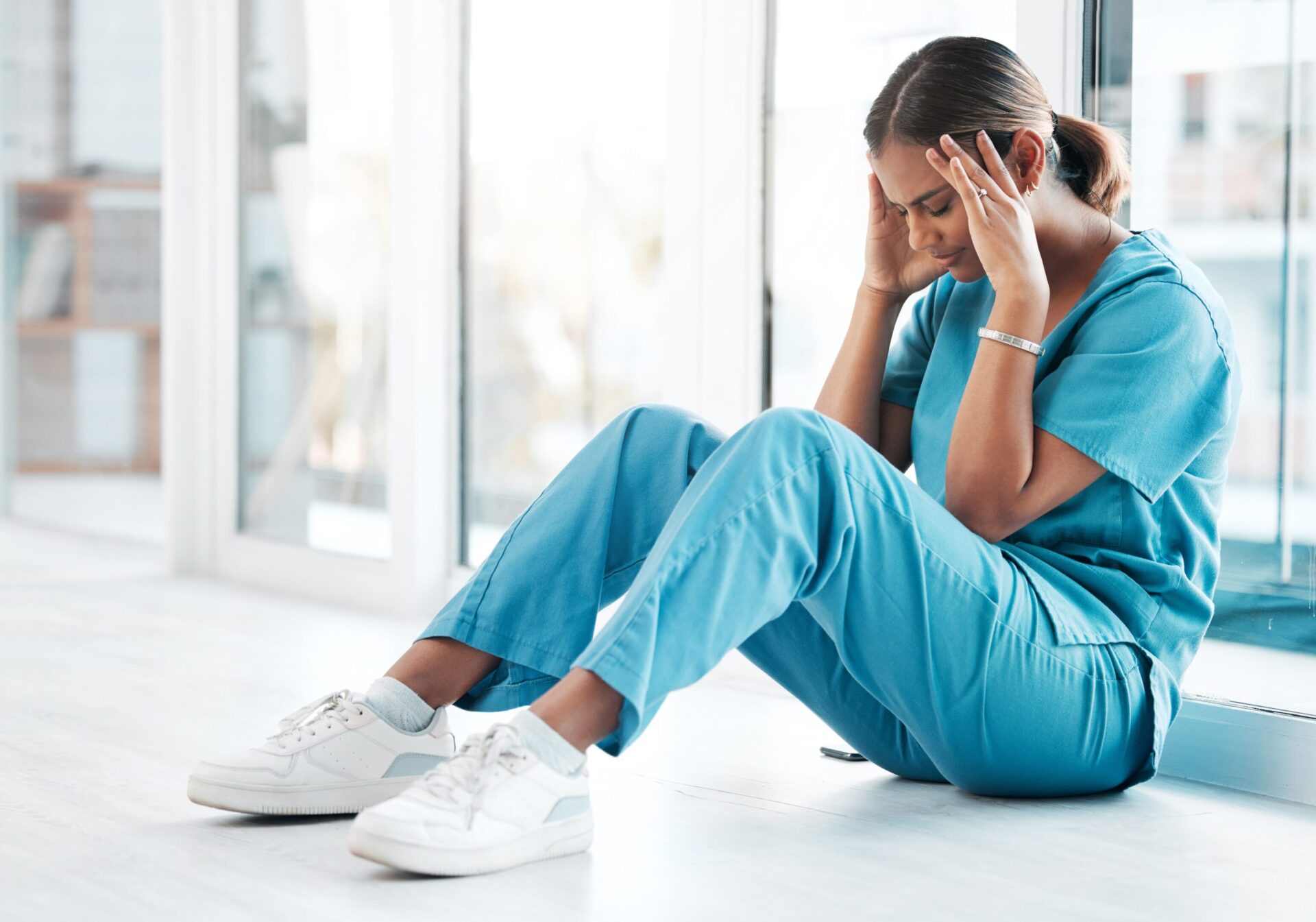 Which condition may increase the potential for Nursing Malpractice - Female nurse sitting on the floor and frustated - The Pagan Law Firm